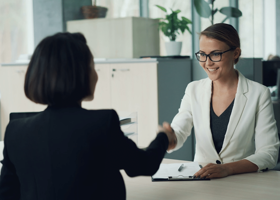 Female physician shaking hand of a woman in black suit jacket