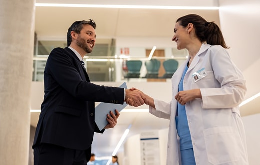 Health insurance agent handshaking with a doctor at the hospital