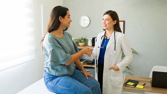 Female doctor shaking hands with female patient in exam room